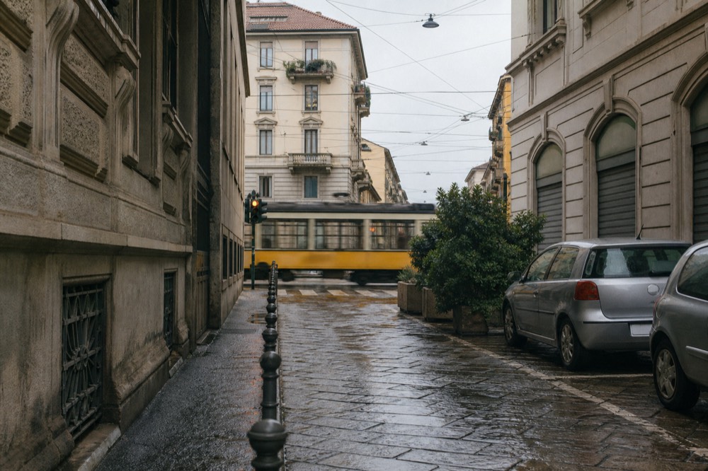 Stone-paved side street in Milan with tram wires and storefronts