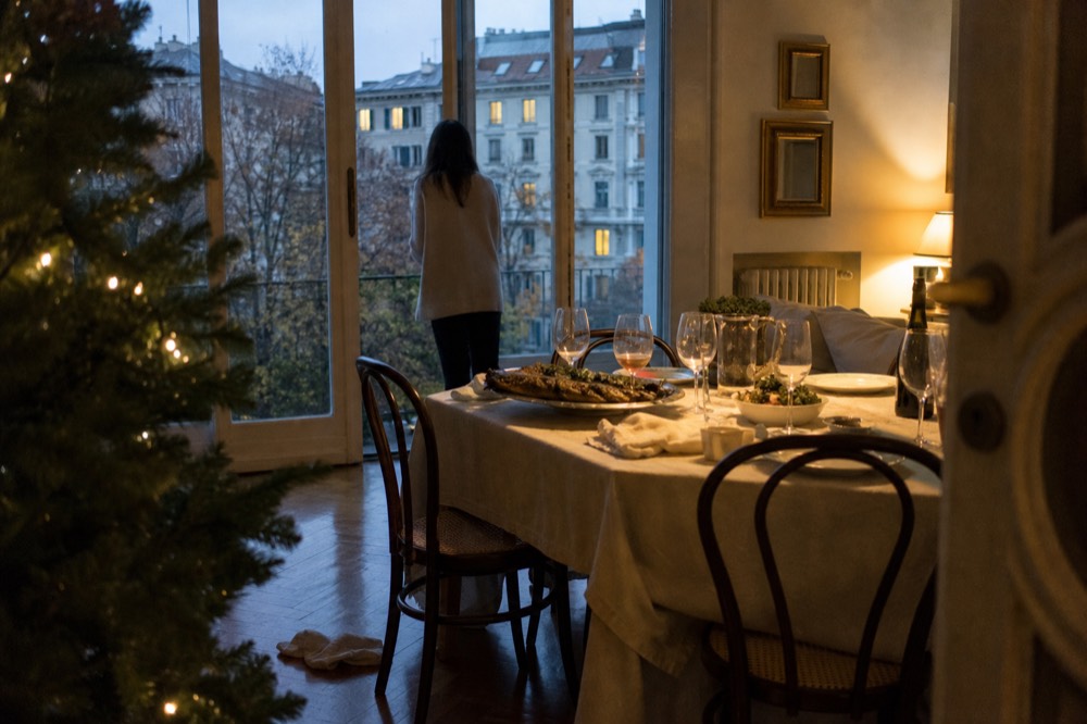 A Christmas Eve table with baked fish, vegetables and wine glasses