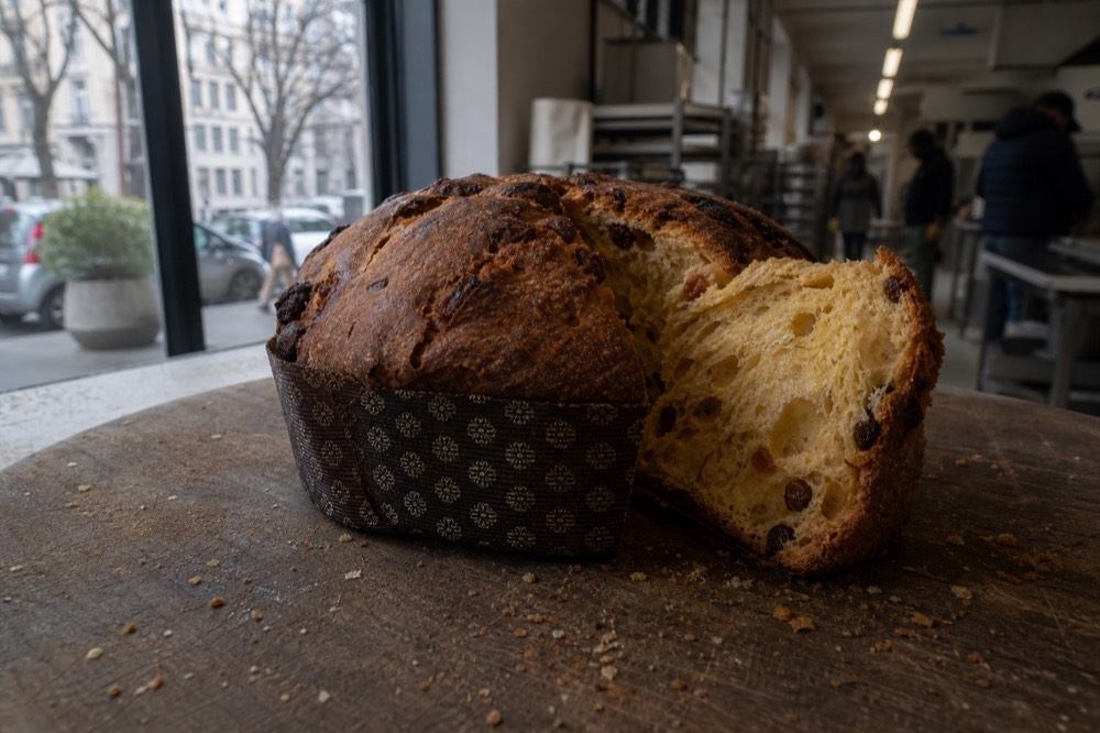 A whole panettone and a sliced wedge on a wooden board