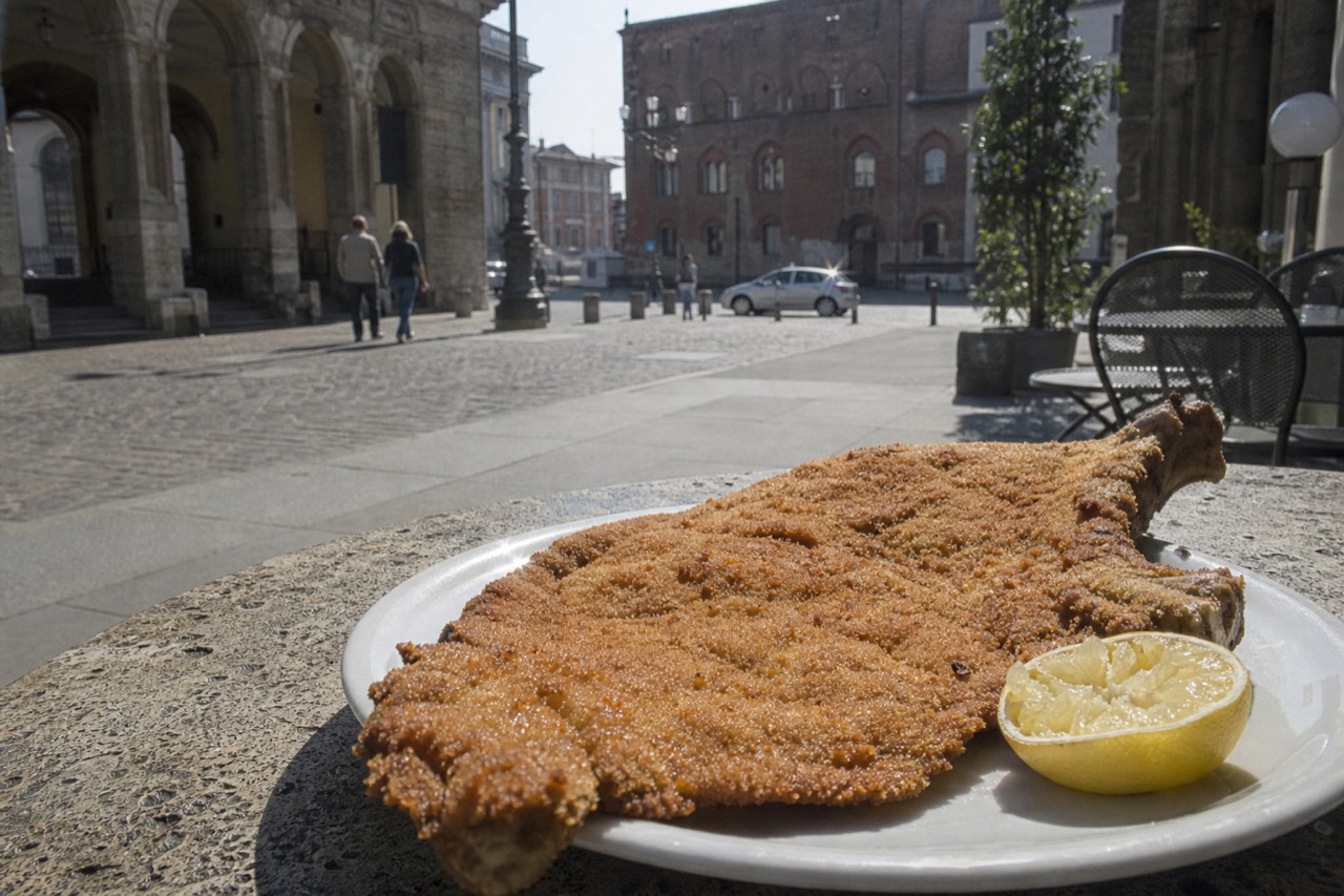 A breaded veal cutlet with bone, golden and crisp on a white plate with lemon