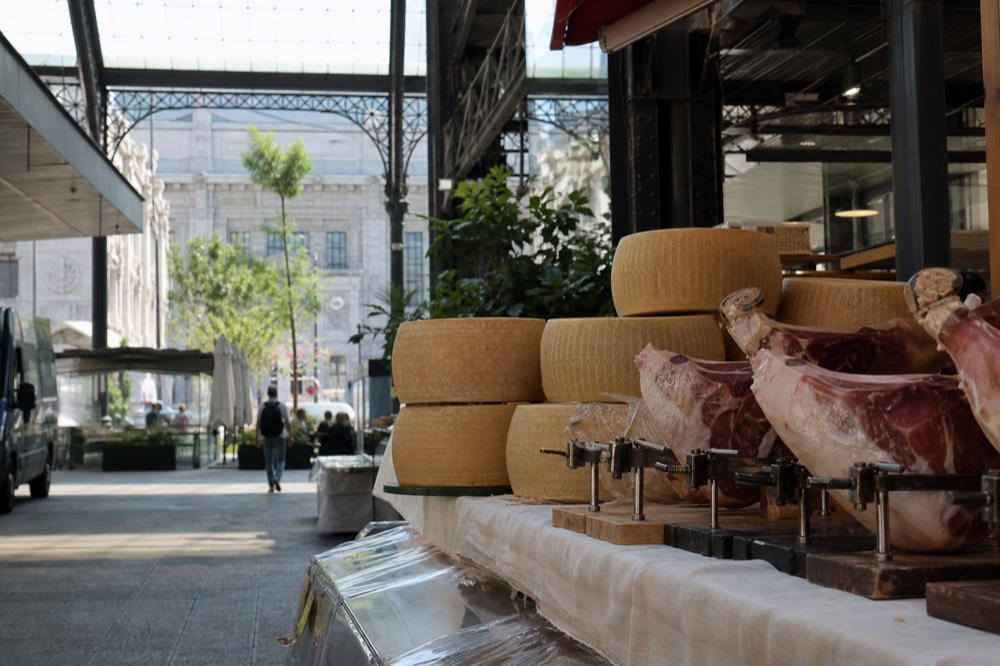 Cured prosciutto and Parmigiano cheese wheels displayed in a shop