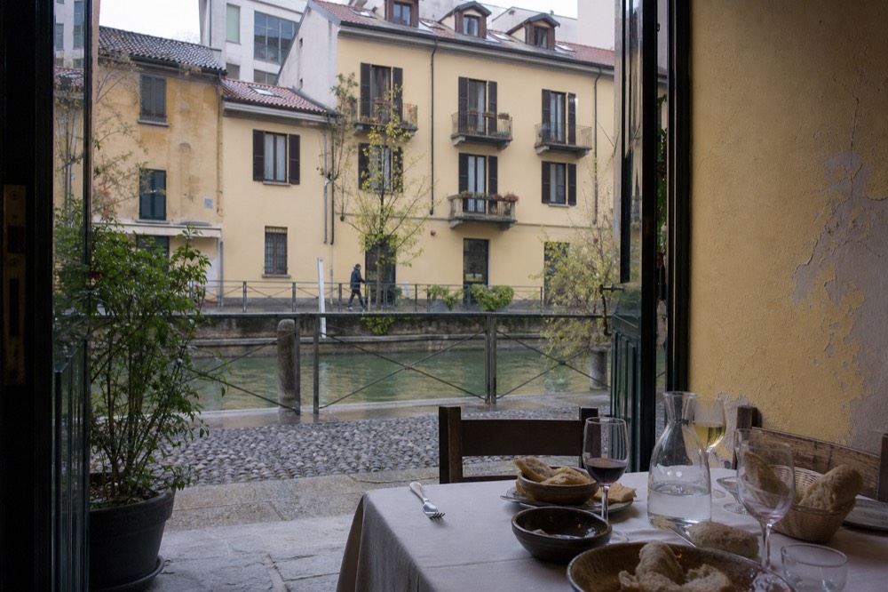 A trattoria table set with bread, water and wine glasses in Milan