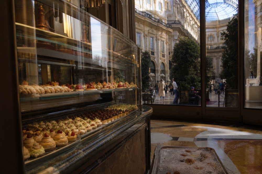 A glass pastry counter filled with miniature cream pastries and fruit tartlets