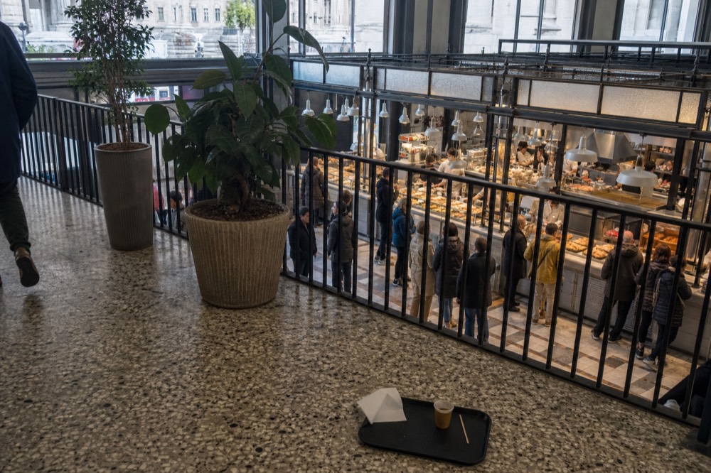 A food hall interior with counters of ready dishes and customers ordering at midday