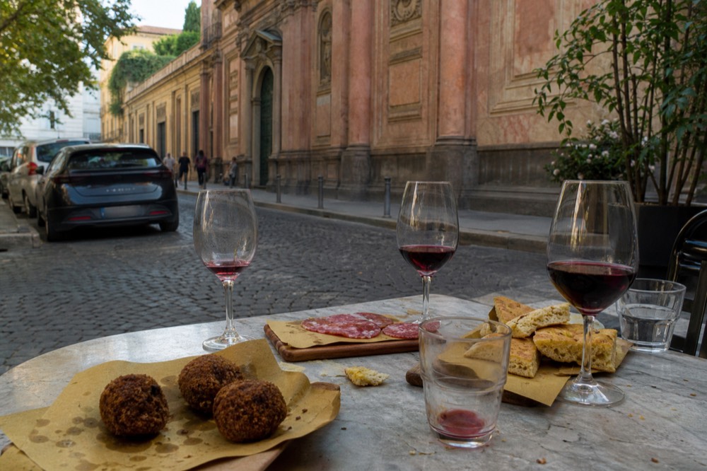 A table spread with Milanese street food snacks and glasses of wine in a small eatery