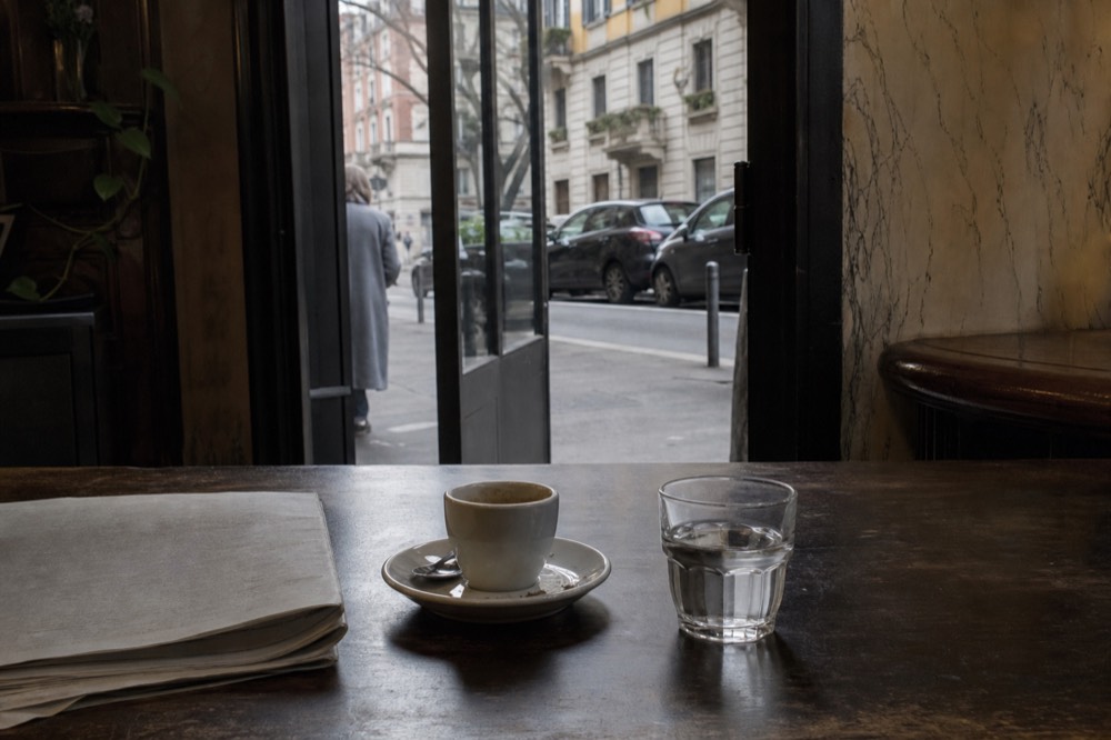 Espresso cup and glass of water on a wooden bar counter in a Milan cafe