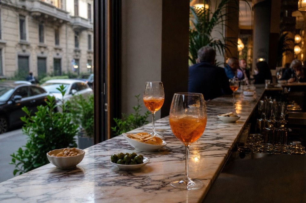 A classic Milan aperitivo spread with spritz glasses and small plates on a marble bar