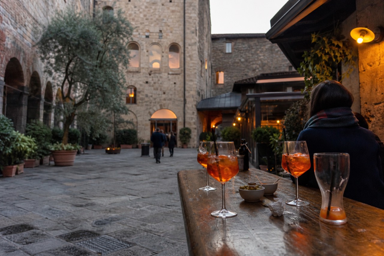 Glasses of spritz and small plates on a wooden bar counter in a Milanese bar