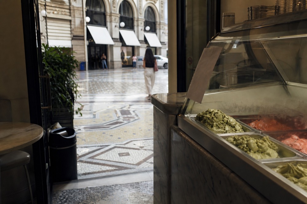 Small gelato shop interior with a marble counter and a handwritten seasonal flavour list on a chalkboard