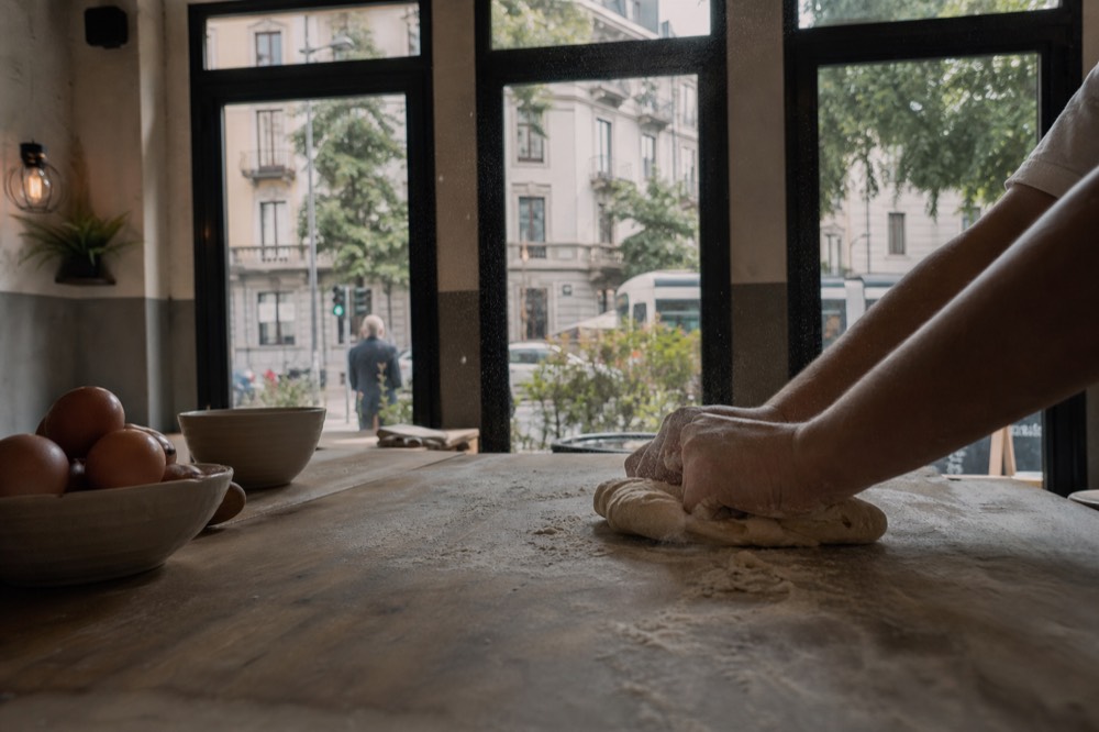 Hands kneading dough on a floured wooden table in a cooking school