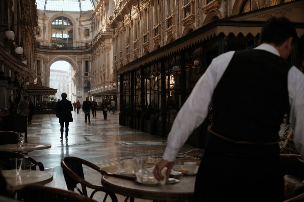 The glass-vaulted arcade of the Galleria Vittorio Emanuele II with café tables under the dome
