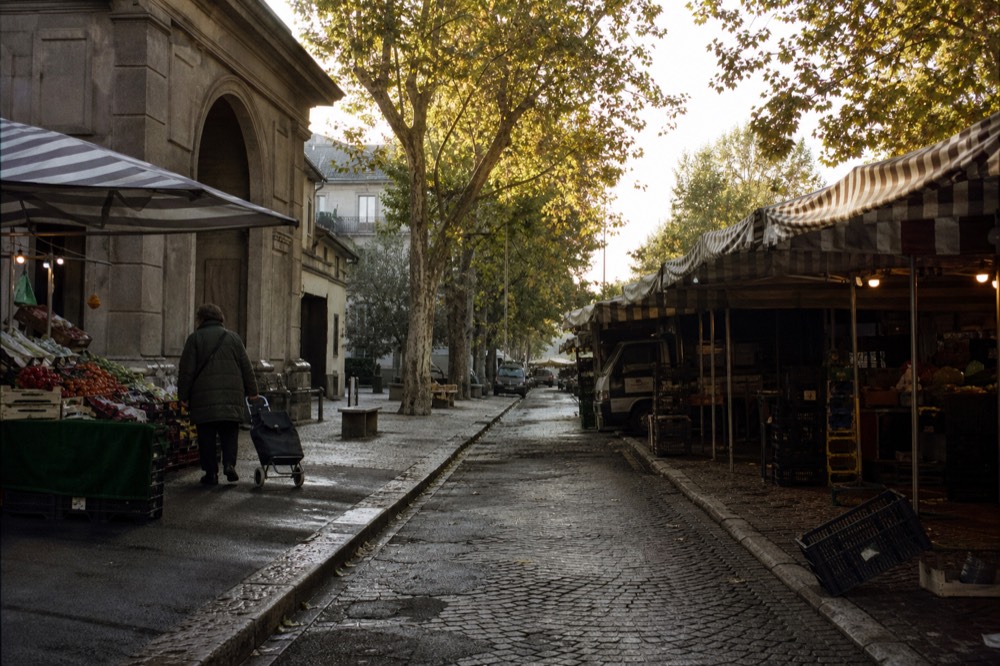 A market street in Milan with awnings and stalls in morning light
