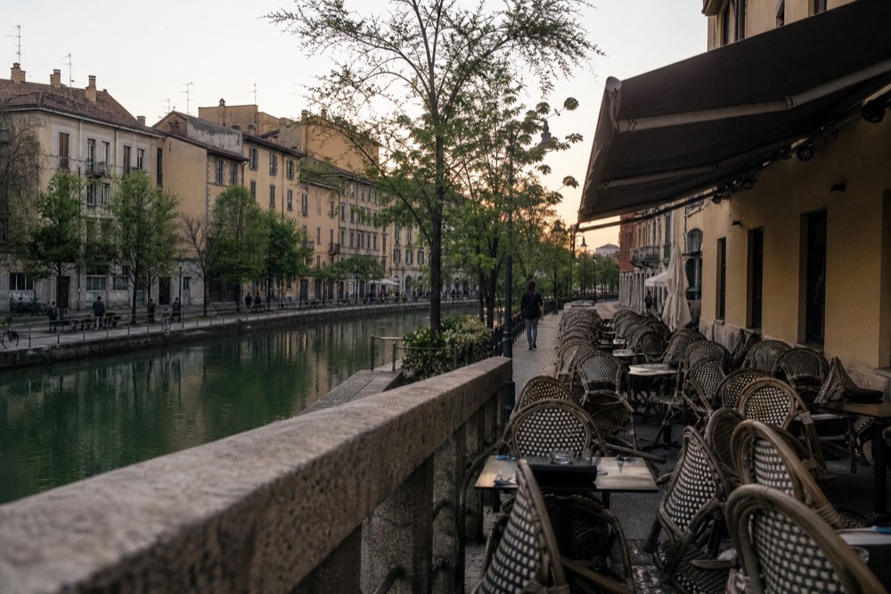 A canal-side bar terrace with empty tables in early evening