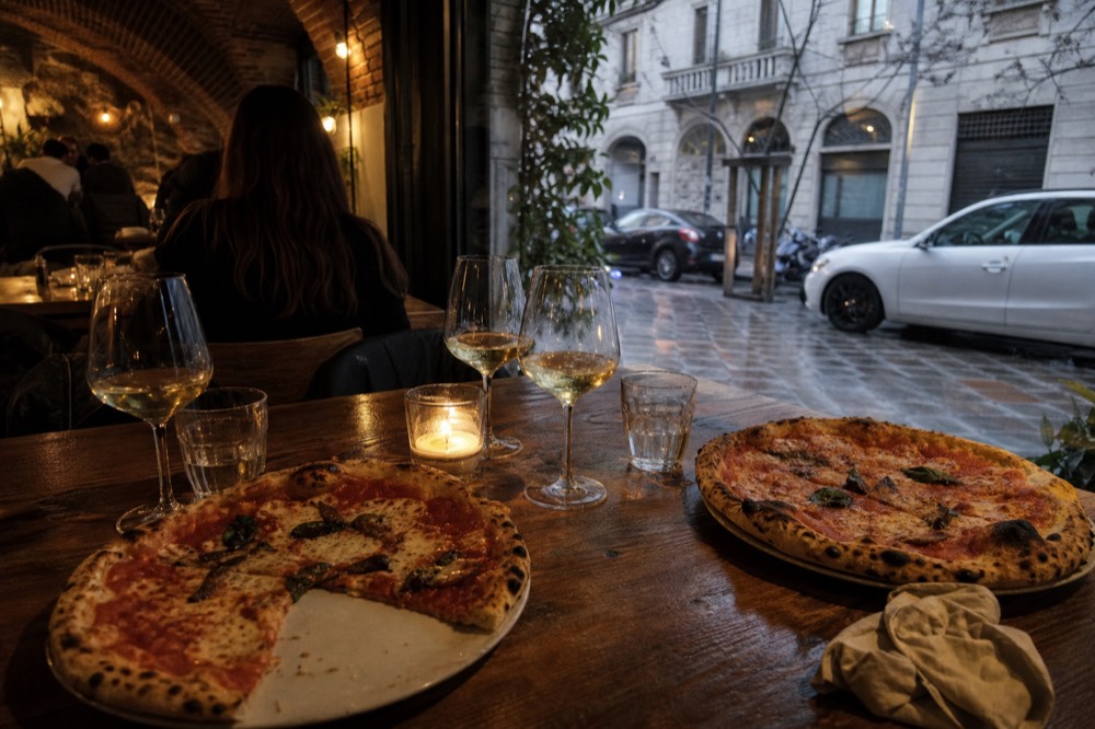 A table set with wine glasses and freshly baked pizzas in a warm restaurant interior