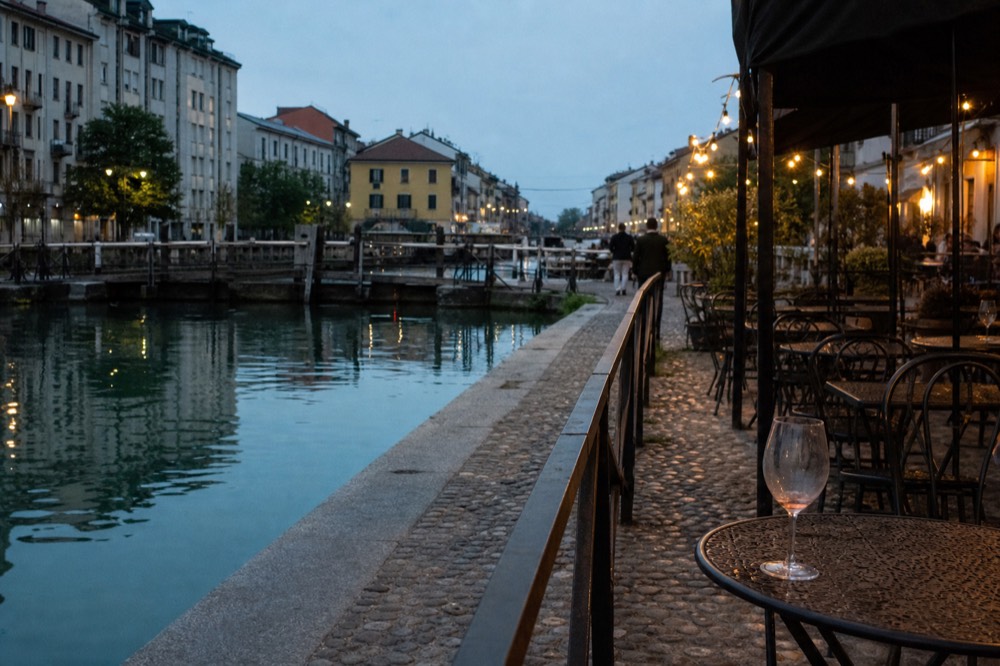 Canal-side street with bar tables in the Navigli district at dusk